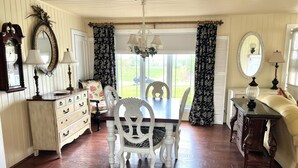 A dining area with a wooden table and white chairs, flanked by a dresser and a cabinet.