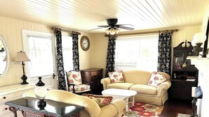 A cozy living room with a sofa, armchair, and coffee table, a wooden cabinet, and a ceiling fan.