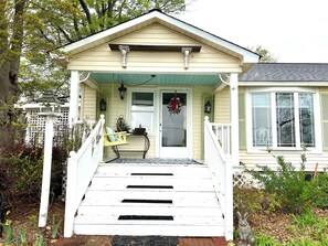 Una casa con portico, una panchina e un piccolo giardino.
