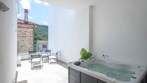 A modern bathroom with a hot tub, a seating area with chairs, and a view of a hillside. - Hotel Palazzo Antonietta (Castellabate)