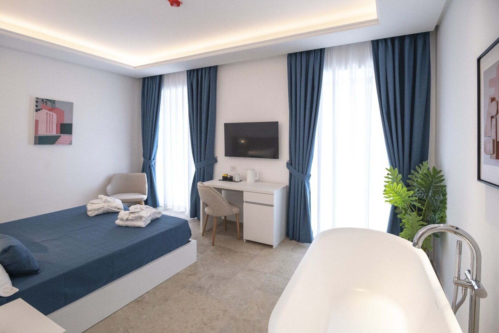 A modern hotel room with a bed, desk, and bathtub.
