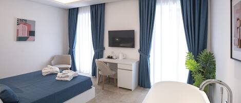 A modern hotel room with a bed, desk, and bathtub.