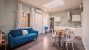 A modern apartment with a blue sofa, dining area, and kitchen. - Huge design apartment in the center of Venice, with private courtyard (Venezia)