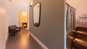 A modern hallway with a dark grey wall, a large mirror, a black chair, and a staircase with wooden steps. - Huge design apartment in the center of Venice, with private courtyard (Venezia)