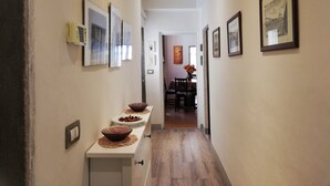 A hallway with framed pictures on the walls, a wooden floor, and a table with bowls at the end.