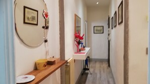 A hallway with a wooden shelf, a mirror, and a framed picture on the wall.