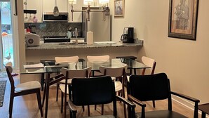 Une cuisine moderne avec un coin repas, comprenant une table en verre, des chaises et un tapis à motifs.