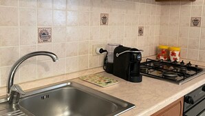 A kitchen with wooden cabinets, a stainless steel sink, a gas stove, and a coffee maker.