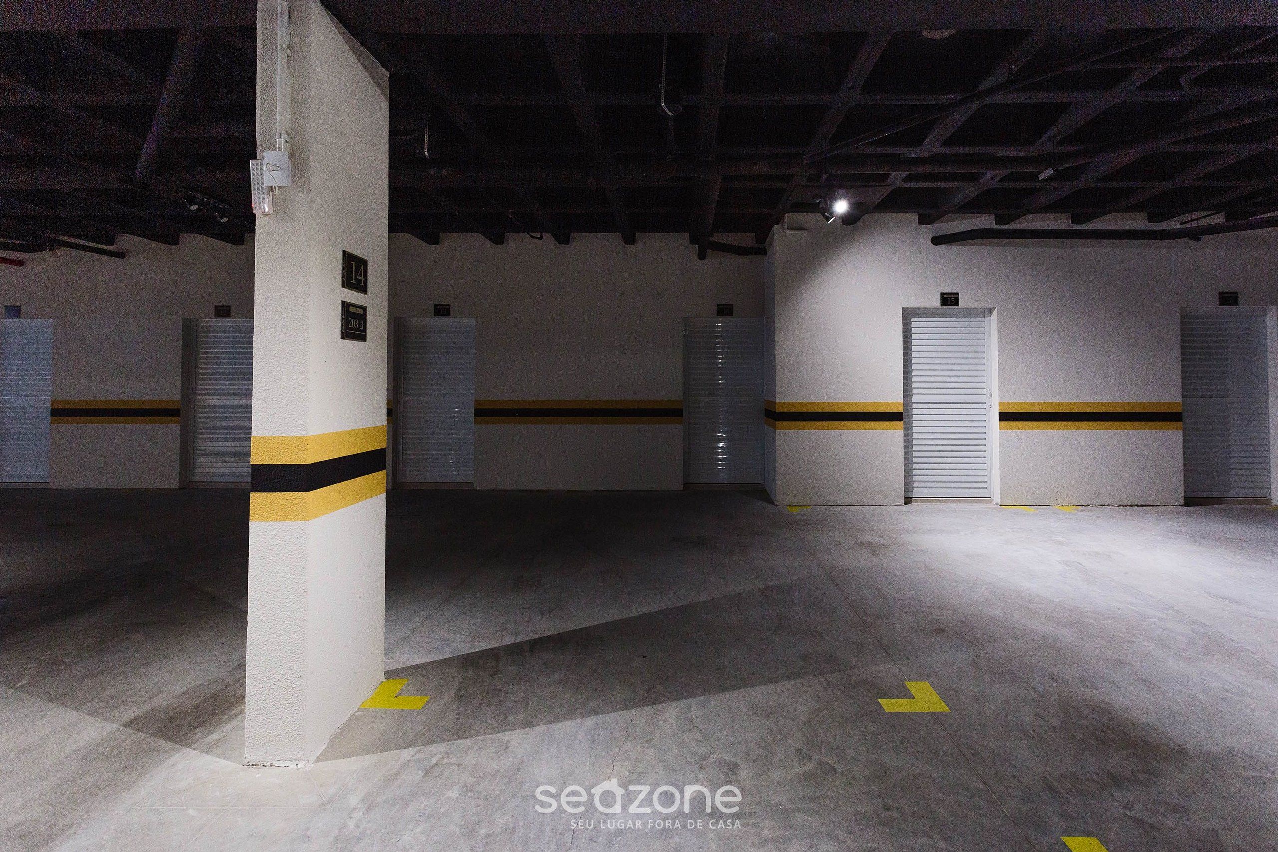 Un aparcament amb pilars de formigó, places aparcament numerades i fletxes direccionals al sòl.