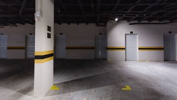 A parking garage with concrete pillars, numbered parking spots, and directional arrows on the floor.