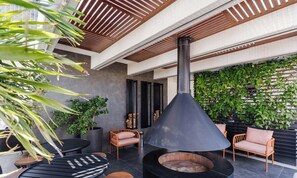 An outdoor patio with a wood-burning stove, seating, and a wall of greenery. - Full Apartment at Ingleses Beach-sc Gge203 (Florianópolis)