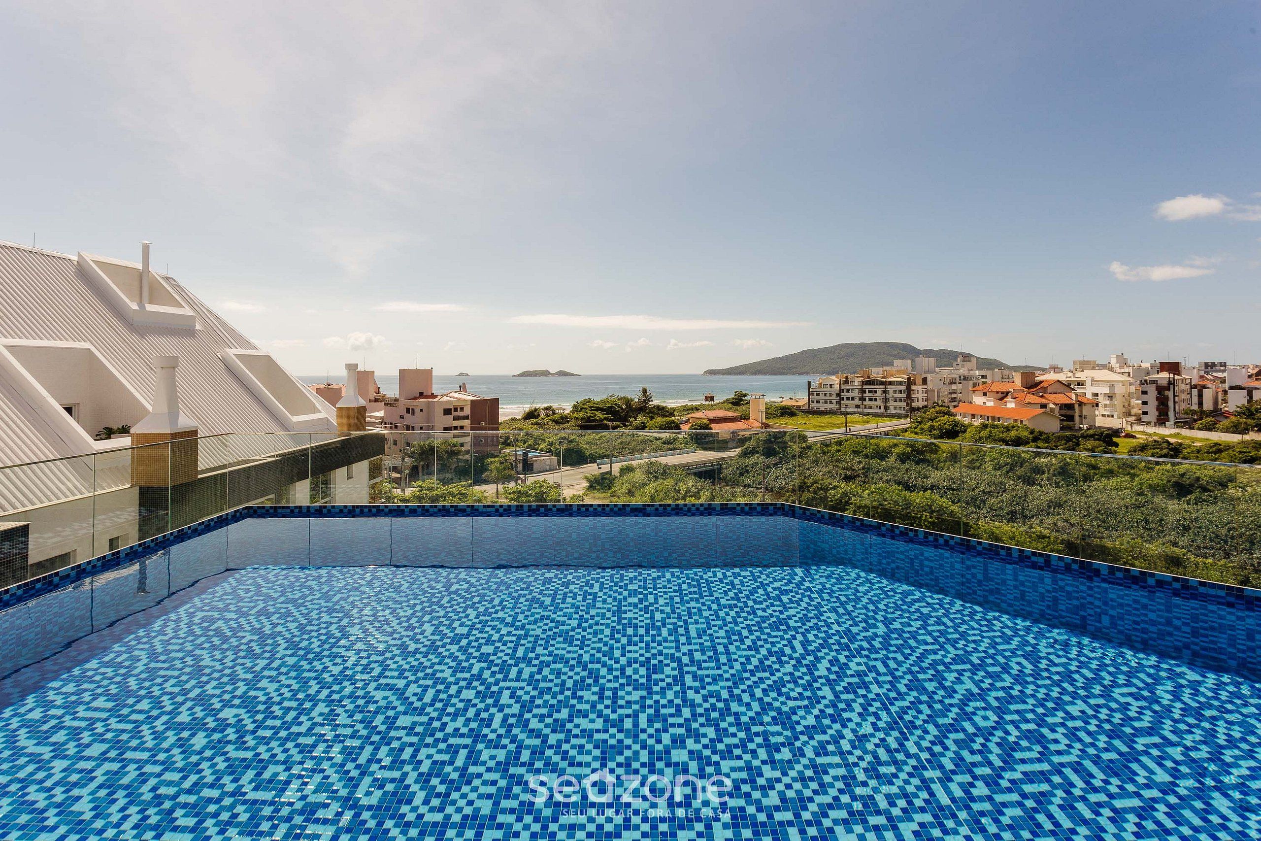 Piscina en la azotea con vistas despejadas al mar y edificios circundantes.