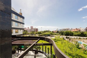 A modern building with a curved balcony overlooking a landscaped area with a pool and greenery. - Full Apartment at Ingleses Beach-sc Gge203 (Florianópolis)