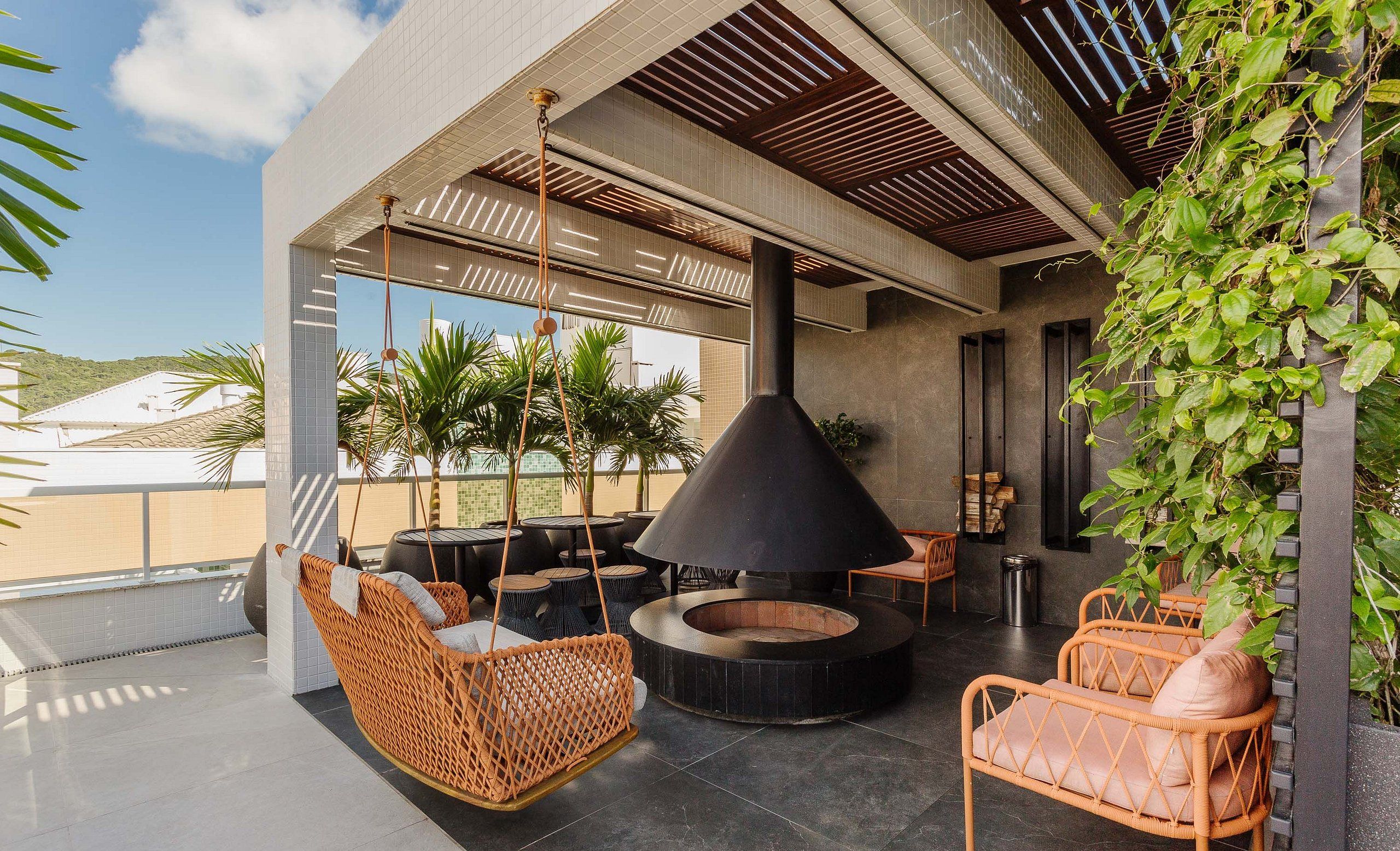 Un espace extérieur aménagé avec des chaises en osier et un foyer central.