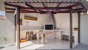 An outdoor kitchen area with a stone table, stools, and a hanging sign. - Cozy Apartment Less Than 100 m From the Beach Gdi2 (Florianópolis)