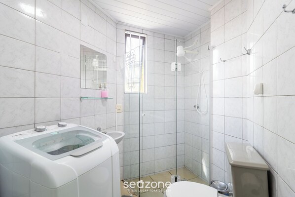 Une salle de bain moderne avec un lave-linge intégré dans un espace vitré, un lavabo et des toilettes.