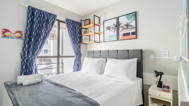 A hotel room with a bed, a bedside table with a lamp, and a window with blue curtains. - Cozy Apartment Less Than 100 m From the Beach Gdi2 (Florianópolis)