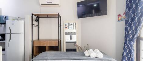 A bedroom with a bed, a TV, a wardrobe, and a desk.