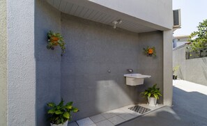 Un baño exterior moderno con un lavabo blanco y plantas en macetas.