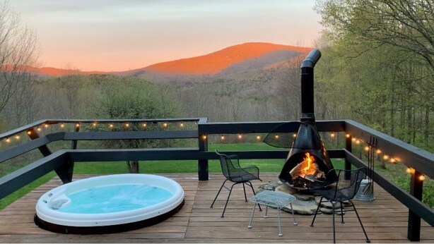 Eine Terrasse mit Whirlpool, Feuerstelle und Lichterketten.