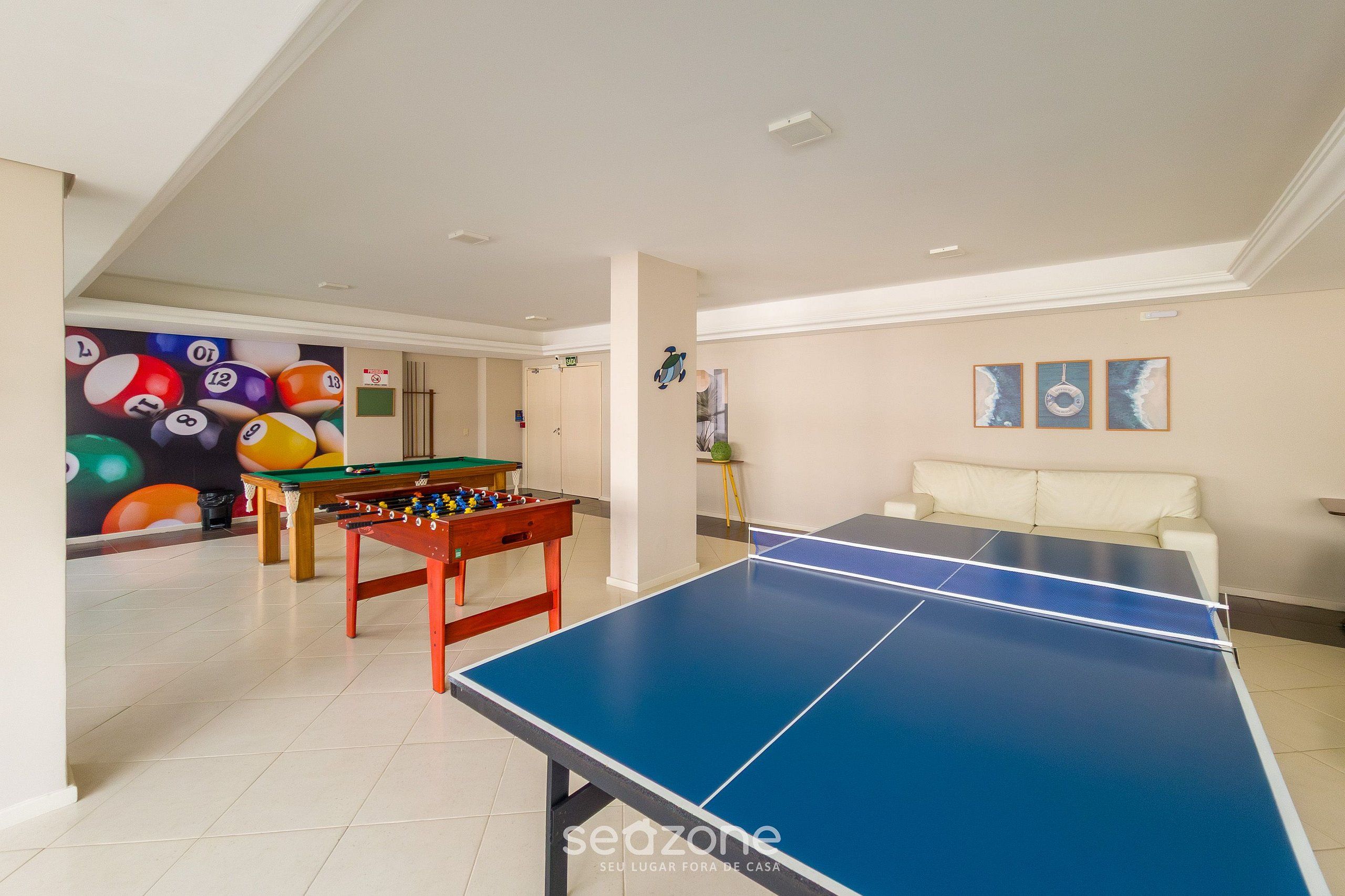 Een ruime kamer met een tafelvoetbaltafel, een pingpongtafel en een biljarttafel.