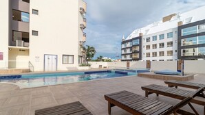 Una piscina con lettini e vista su edifici moderni.