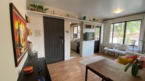 Ein modernes Wohnzimmer mit Holzboden, einem Esstisch und einer Küche im Hintergrund.