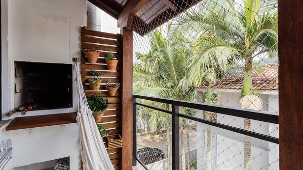 Ein Balkon mit Holzgeländer, einem an der Wand befestigten Fernseher und Kübelpflanzen.