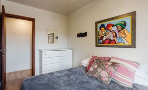 A bedroom with a bed, a dresser, a door, a framed picture, and a wall-mounted artwork. - Quiet Apartment 1 mi From Canasvieiras bea Fml202 (Florianópolis)