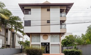 Un edificio moderno de dos pisos con techo plano, ventanas grandes y un balcón pequeño.