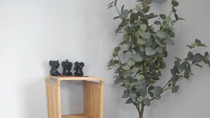 A wooden shelf unit with three shelves, a potted plant, and a small decorative vase on a tiled floor.