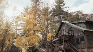 Een rustieke blokhut met een houten gevel, een balkon en een bordje met de tekst 'Maverick Lodge'.