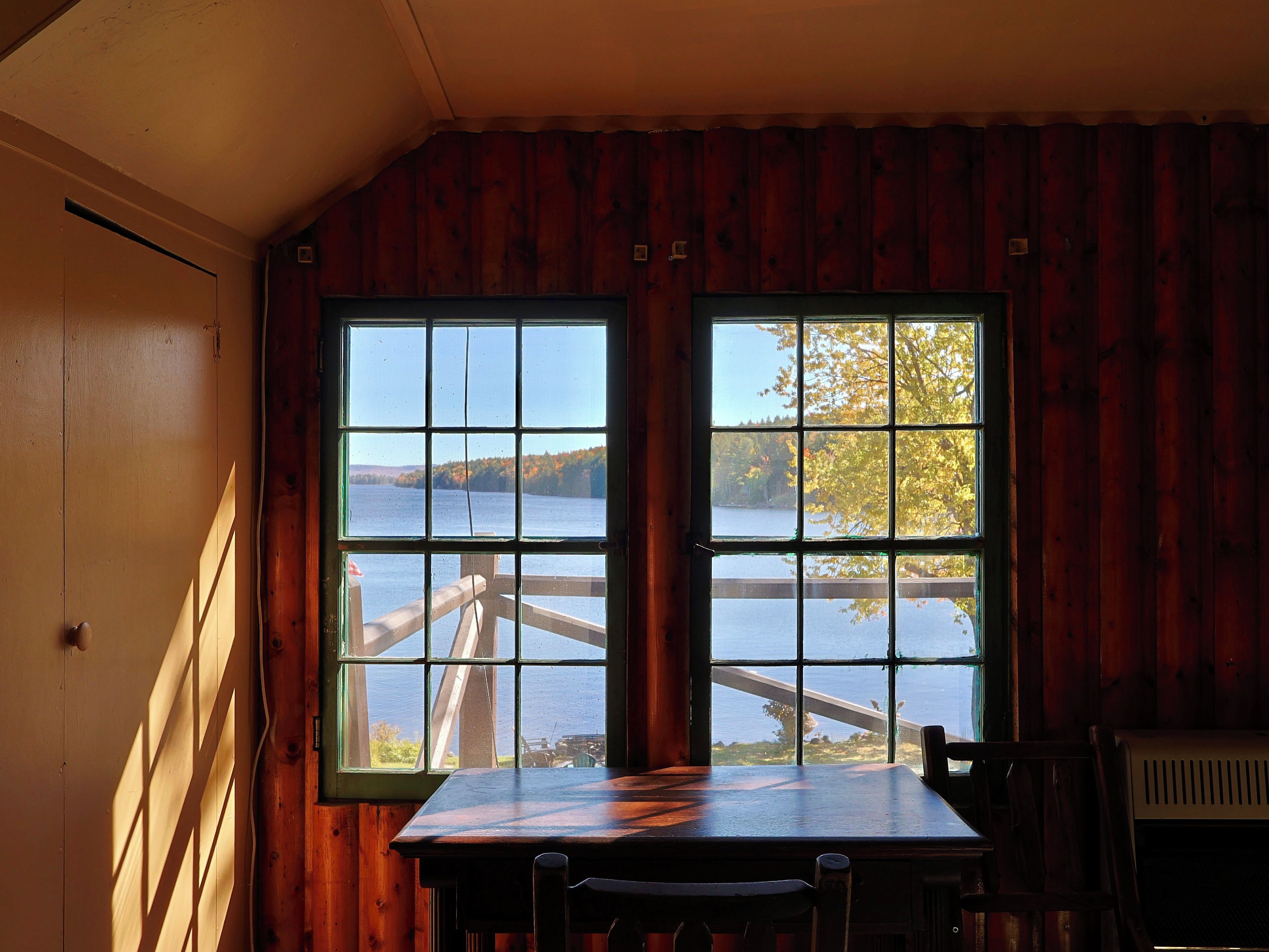 A room with a large window overlooking a body of water and a wooden deck.