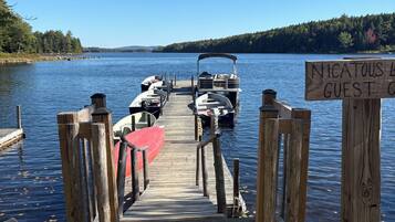 A wooden dock leading to a lake with boats moored at the end.
