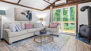 Ein Wohnzimmer mit einem beigen Sofa, gemusterten Kissen, einem Glastisch und einer rustikalen Decke.