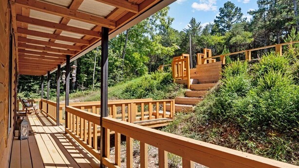 Eine Holzterrasse mit Geländern, einer Treppe und einer Laterne.