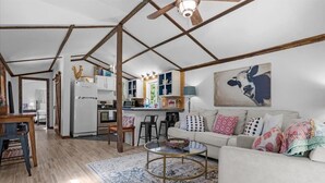 Ein geräumiges Wohnzimmer mit einer Couch, einem Couchtisch und einer Küchenzeile im Hintergrund.