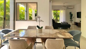 Ein modernes Wohnzimmer mit einem Glastisch, bequemen Sitzmöglichkeiten, einer Couch und einem Fernseher.