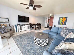 A modern living room with a sofa, coffee table, and a dining area with chairs.