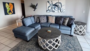 A modern living room with a sectional sofa, two round coffee tables, and decorative wall art.