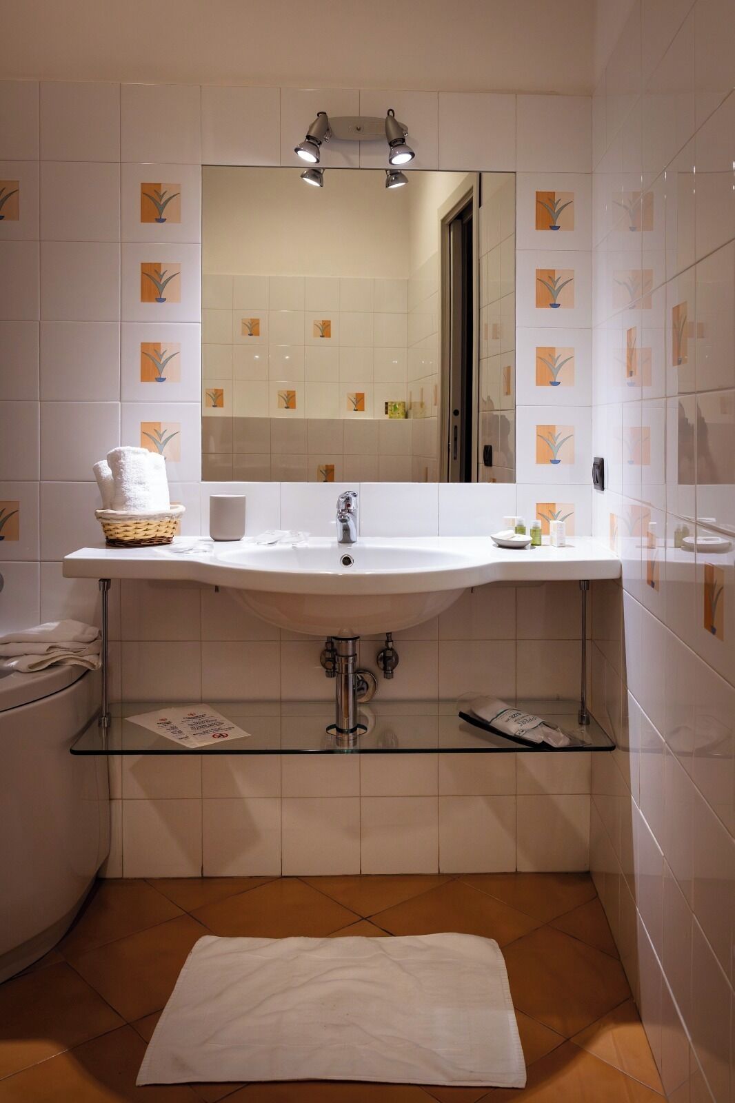 A bathroom with a white sink, a mirror above it, and a tiled floor.