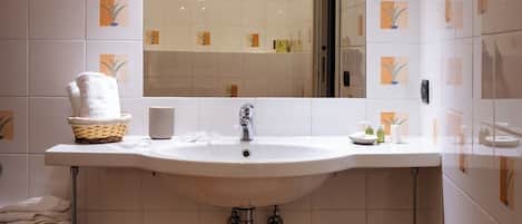 A bathroom with a white sink, a mirror above it, and a tiled floor.