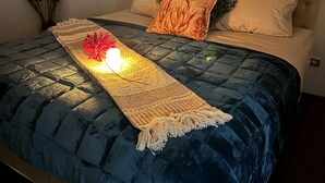 Un lit avec une couvre-lit matelassée bleue, un coussin décoratif et un tableau accroché au mur au-dessus du lit.