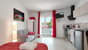 A modern hotel room with a bed, a sofa, a small table, a kitchen area with a microwave, and a TV. - Fantastico 1 with large balcony, air conditioning, kitchen, parking, BBQ, great for couples (Puerto de la Cruz)