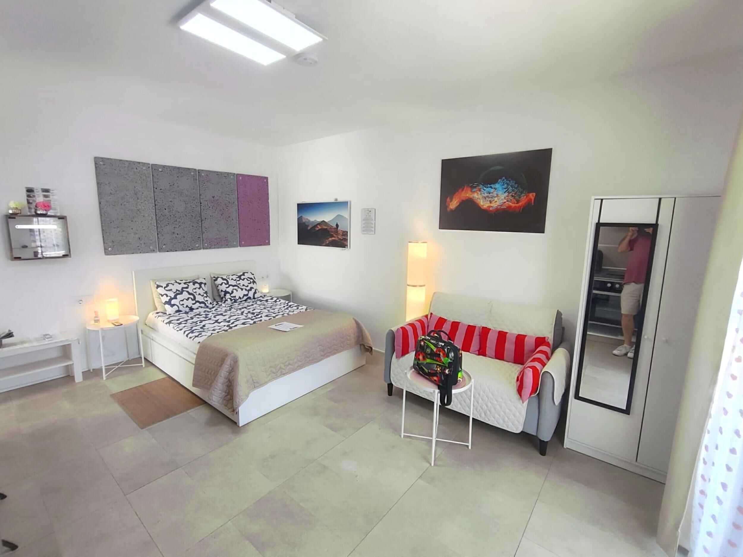Een moderne slaapkamer met een bed, een slaapbank, een klein tafeltje en een kledingkast.