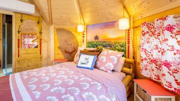 A wooden room with a bed, a wall painting, and a hanging lamp.