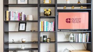A bookshelf with various decorative items and a 'GUEST READY' sign.