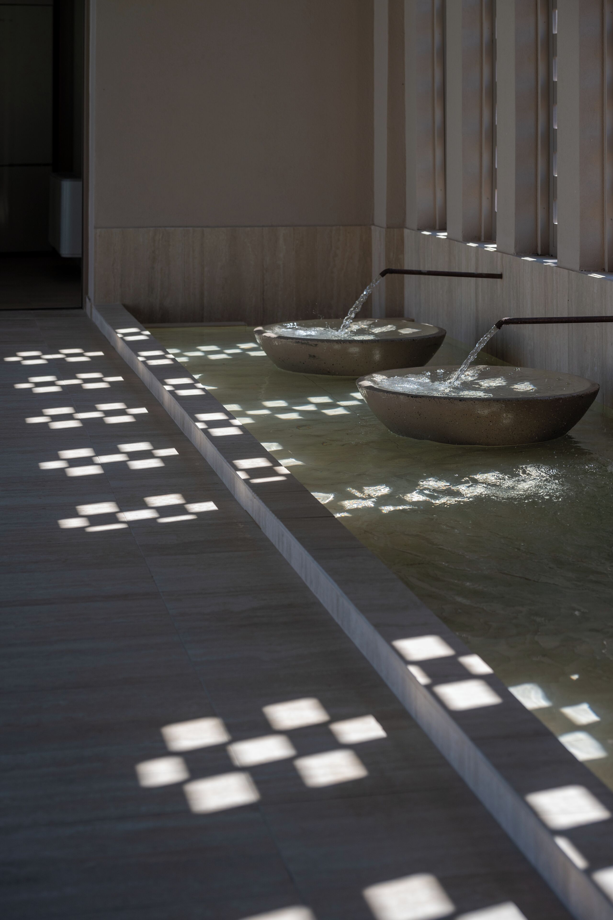 A corridor with a water feature and patterned lighting.