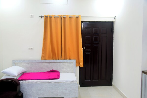 Une chambre à coucher avec un lit, une porte noire et un rideau orange.