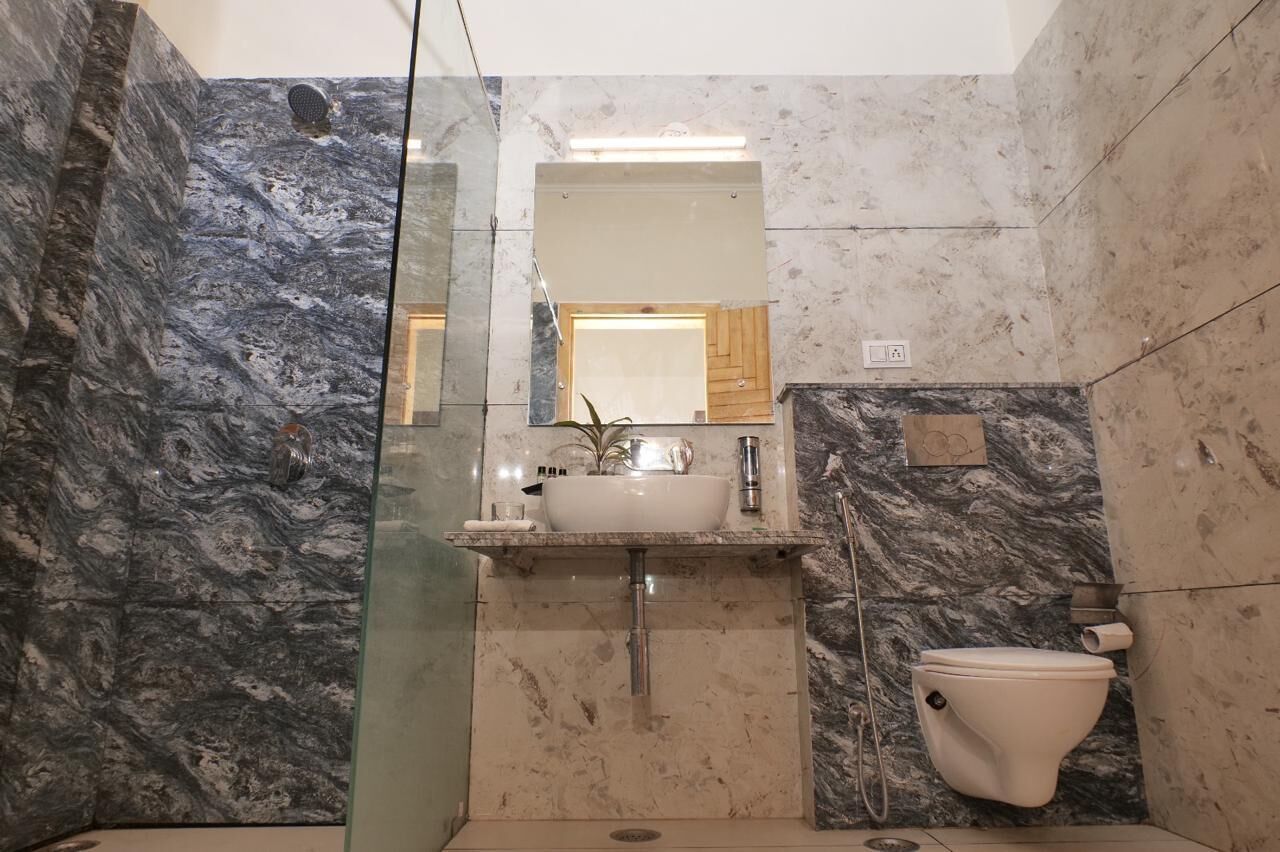 A bathroom with a glass shower enclosure, a white sink with a mirror above it, and a toilet.